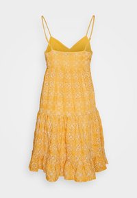 Robe midi jaune sans manches avec fines bretelles et broderie florale ajourée, avec un ourlet à volants superposés.