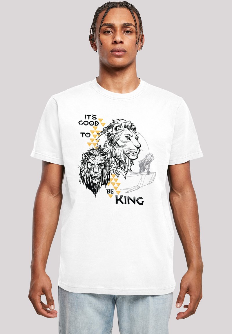 Vit bomullst-shirt med svarta och guld lejon-grafik, texten "DET ÄR BRA ATT VARA KUNG" och geometriska detaljer. Kort ärm och rundad halsringning.