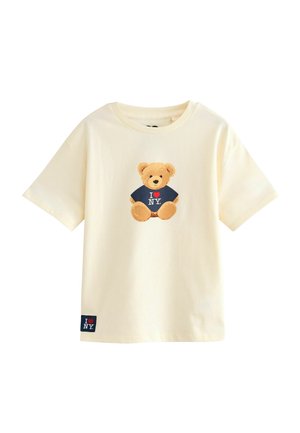 Kridhvid kortærmet t-shirt med et grafik af en brun bjørn iført en marineblå "I ❤️ NY" t-shirt og et sort label med samme tekst.
