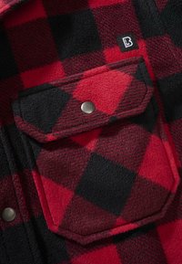 Rotes und schwarzes kariertes Flanellhemd mit strukturiertem Stoff, metallenen Druckknöpfen und einer Brusttasche mit eckigem Design.