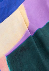 Kleurrijke stof met abstracte, elkaar overlappende blokken van paars, geel en groen. Materiaal lijkt glad met een lichte textuur.