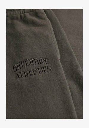 Pantalons de survêtement vert olive foncé en tissu doux, arborant un logo brodé "Superdry Athletics" dans une couleur contrastante.