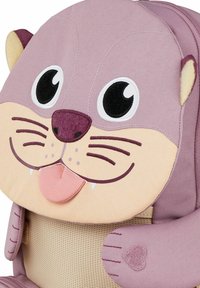 Lila Stoffrucksack in Form eines Ottergesichts, mit großen Augen, Schnurrhaaren und einer Zunge. Strukturierte Ohren und herzförmige Akzente.