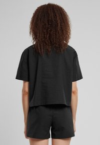 Set di top corto e pantaloni shorts neri in tessuto testurizzato, caratterizzato da maniche corte e una vestibilità comoda e ampia.