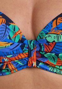 Top bikini multicolore con un vivace motivo a foglie tropicali in blu, verde e arancione; tessuto arricciato e coppe triangolari.