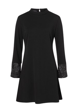 Robe noire à manches longues, avec un col montant et des accents en dentelle sur les poignets. Confectionnée dans un tissu lisse, design à mi-genoux.
