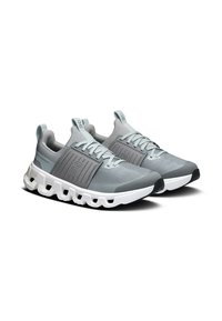 Baskets de sport grises avec une tige en maille, un panneau latéral texturé, une semelle blanche, une base rembourrée et un système de laçage. Détails en bleu clair.