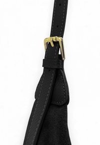 Bracelet en cuir noir avec une boucle en métal doré, mettant en avant des coutures visibles et des accents en suede, présentant une surface texturée et un design élégant.