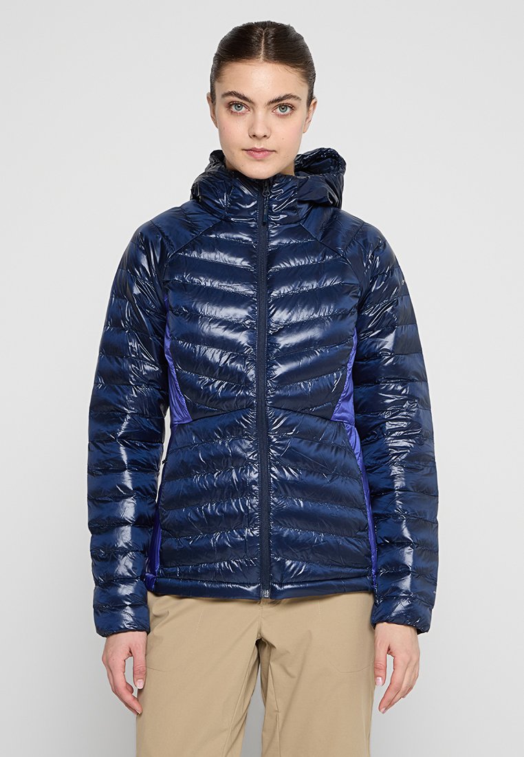 Veste matelassée de couleur bleu marine avec une texture brillante, capuche attachée et panneaux latéraux violets. Dotée d'une fermeture éclair à l'avant et de poignets élastiques.