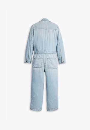 Tuta in denim azzurro chiaro con maniche lunghe, tasche frontali e design a gamba dritta. Presenta un colletto e dettagli con bottoni.