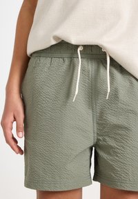 Ljusgröna texturerade shorts med elastisk midja och dragsko. Kort längd, med ett subtilt våffelmönster och sydd fåll.
