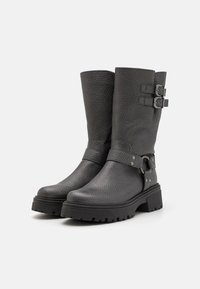 Zwarte leren laarzen met een gezoete textuur, halverwege de kuit, met zilveren gespen en riemen, stevige rubberen zolen met profiel.