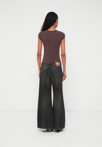 Σκούρα γκρι τζιν με φαρδιά μπατζάκια και ξεθωριασμένη υφή, με ορθογώνιο σχέδιο στο πίσω μέρος. Συνδυασμένα με εφαρμοστό καφέ τοπ με κοντά μανίκια.