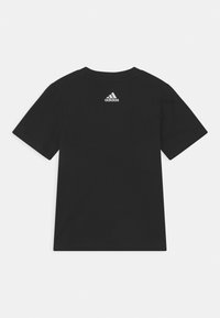 Musta lyhythihainen t-paita, jossa on pieni valkoinen Adidas-logo sijoitettuna keskelle yläselkää yksinkertaista valkoista taustaa vasten.