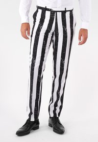Čierno-biele vertikálne pruhované nohavice s bodkovaným vzorom, vyrobené z hladkej látky, opatrené pásom a so štíhlym strihom.