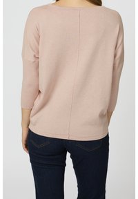 Ljusrosa stickad topp med 3/4 ärmar och en detalj med bakseam, ihopparad med mörkblå jeans med fickstickning.