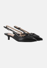 Zapatos slingback de cuero negro con punta afilada, detalles de encaje y un tacón bajo. Presenta tachuelas decorativas a lo largo de las correas.