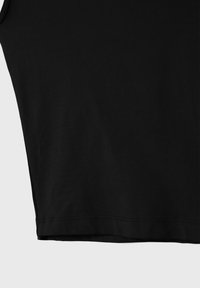 Black fabric close-up showing the lower edge of a garment with clean stitching against a light background.