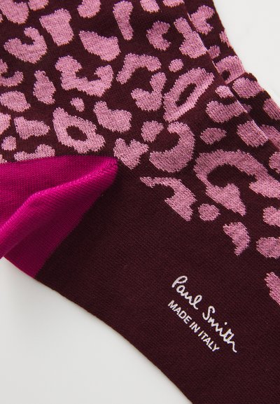 Calze con stampa leopardata in bordeaux scuro e rosa. Presentano una texture liscia con un risvolto rosa in contrasto. Logo ricamato alla caviglia. Prodotte in Italia.