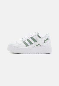 Witte sportieve sneakers met groene accenten; met een bovenwerk van getextureerd leer, een drie-strepenontwerp en een dikke witte rubberen zool.