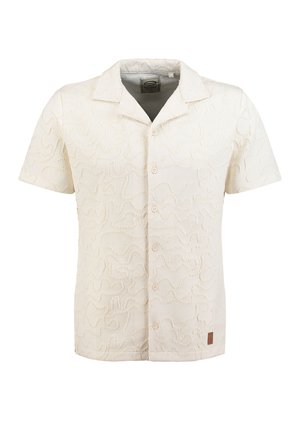Chemise crème à manches courtes avec des boutons et un motif abstrait texturé, avec une petite étiquette marron près de l'ourlet.