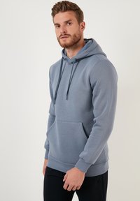 Sweatshirt à capuche gris en tissu doux, avec une poche avant, un cordon de serrage ajustable et des poignets et un ourlet côtelés pour un ajustement confortable.