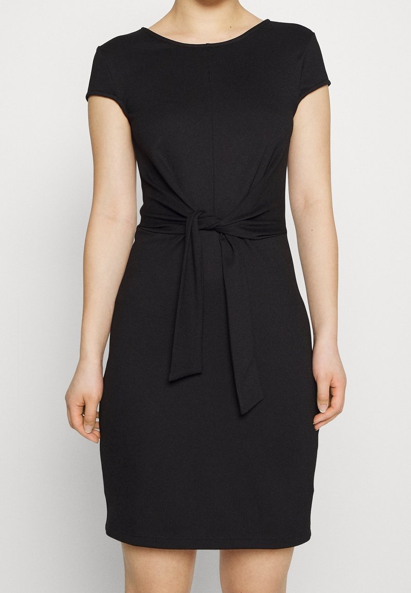 Černé šaty s kulatým výstřihem a krátkými rukávy. Mají uzlový detail v pase a jsou vyrobeny z hladké, elastické tkaniny.