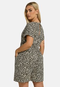 Leopardmönstrad jumpsuit med korta ärmar, knytdel i midjan, fickor och en nyckelhålsdetalj på ryggen. Tillverkad av lättviktig tyg.