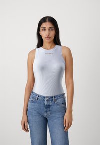 Canottiera a coste blu chiaro con scollatura rotonda, caratterizzata dalla scritta dorata "PINKO". Abbinata a jeans in denim blu chiaro a vita alta.