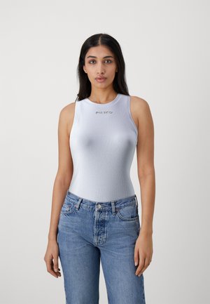 Canottiera a coste blu chiaro con scollatura rotonda, caratterizzata dalla scritta dorata "PINKO". Abbinata a jeans in denim blu chiaro a vita alta.