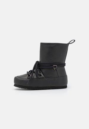 Botte d'hiver noire avec semelle épaisse, bout rond, tige haute et lacets entourant la cheville, maintenus par des œillets métalliques, sur fond blanc.