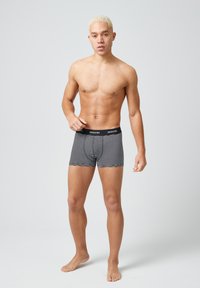 Zwart-witte gestreepte boxershorts met een zwarte tailleband waar "SNOCKS" op staat. De stof lijkt glad en sluit nauw aan op het lichaam.