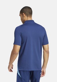 Marineblauwe polo met korte mouwen, een kraag en een gladde textuur. Opvallend ontwerp met contrasterende lichtblauwe accenten aan de zijkanten.