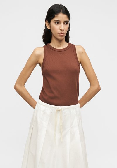 Καφέ ριγωτό αμάνικο τοπ με στρογγυλή λαιμόκοψη, σε συνδυασμό με λευκή, ψηλόμεση, πλισέ φούστα με κορδόνι στη μέση. Χωρίς εμφανή σχέδια.
