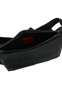 Borsa a tracolla nera in tessuto con chiusura a zip, dotata di un'etichetta rossa "HUGO" all'interno e una texture liscia. Design compatto e lineare.