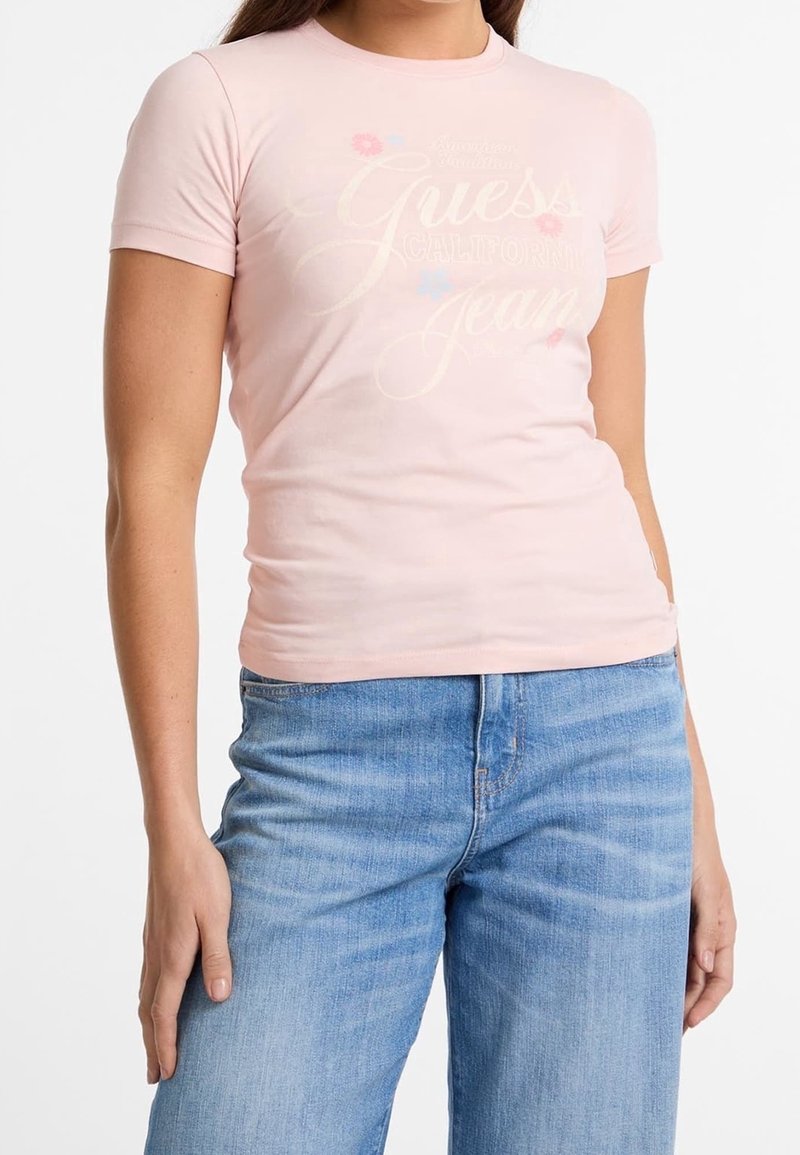 Růžové bavlněné tričko s krátkými rukávy, s nápisem "Guess California Jeans", zdobené malými květinovými vzory v modré a růžové barvě.