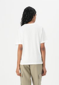 Hvid bomulds T-shirt med korte ærmer og rund hals. Stoffet ser blødt og glat ud, velegnet til afslappet brug.