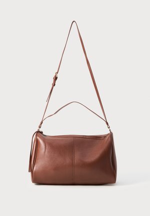 Bolso de hombro de cuero marrón con una forma curva, larga correa ajustable y un brillo sutil. Cuenta con un cierre superior y un detalle de borlas en el lateral.
