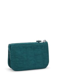 Tealrits portemonnee gemaakt van gestructureerd materiaal. Heeft een contrasterende stitching langs de rits en een compacte, ronde vorm.
