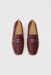 Mocassini in pelle bordeaux con hardware in argento con logo MK sulla fascia, dotati di punta rotonda e dettagli cuciti sulla tomaia.