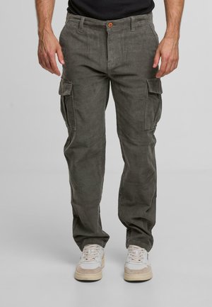 Pantalons cargo en velours côtelé vert olive, avec une coupe droite, poches avant et poches cargo latérales, associés à des baskets blanches.