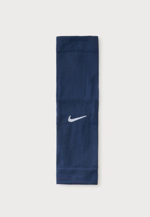 Διπλωμένη μπλε σκούρα αθλητική κορδέλα Nike με λευκό λογότυπο Swoosh στη μέση πάνω σε ανοιχτό φόντο.