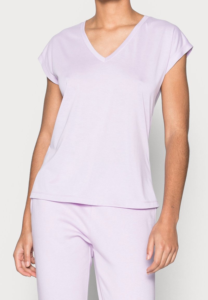 Top à manches courtes violet clair avec col en V, fabriqué en tissu doux, offrant une coupe décontractée et une texture lisse, avec un design simple et épuré.