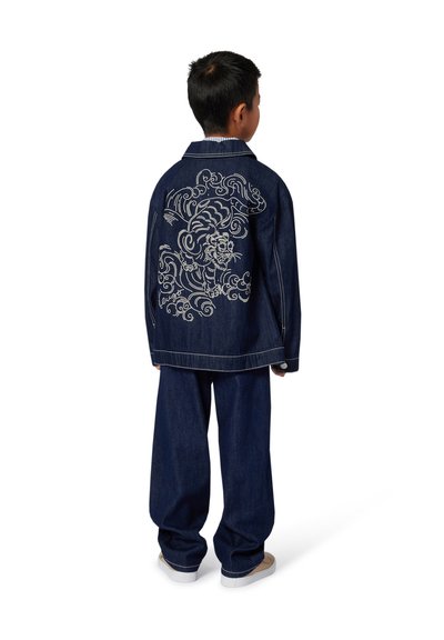 Veste en denim avec un grand motif brodé blanc dans le dos, associée à un jean ample assorti. Couleur : bleu foncé.