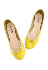 Ballerine gialle in pelle con punta rotonda, bordo elasticizzato e un fiocco decorativo sul davanti. Texture liscia e design minimalista.