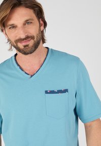 Lichtblauw katoenen V-hals T-shirt met een borstzak met een ankerpatroon, korte mouwen en een zachte textuur.