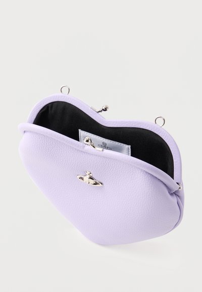 Πορτοφολάκι για κέρματα από δέρμα με υφή λεβάντας και ασημένιο κούμπωμα, ανοιχτό για να αποκαλύπτει μαύρη υφασμάτινη επένδυση και μικρή εσωτερική ετικέτα με έμβλημα λογότυπου.