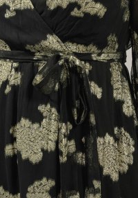 Vestido de tela negra con patrones florales metálicos dorados y un cinturón de lazo en la cintura.