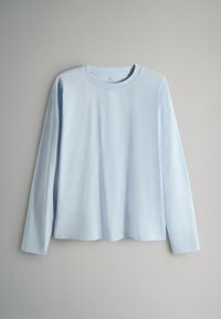 Gaiši zils garām piedurknēm T-krekls mīkstā audumā ar apaļu kakla izgriezumu un taisnu apakšu. Raksturīgas nedaudz nokarenas plecu šuves.