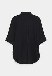 Chemise noire avec un col à revers, manches courtes et coupe ample. Présente un détail plissé au dos et une texture douce. Design simple.